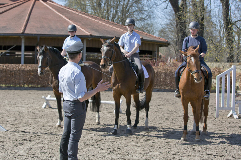 Reitunterricht Moritzburg, Auszubildende halten ihre Pferde und hören dem Ausbilder zu